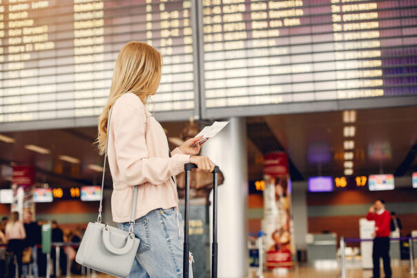 Een vrouw staat met haar vliegticket in haar hand op het vliegveld