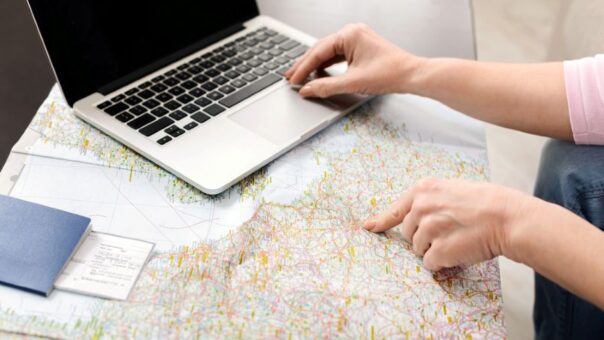 Vrouw plant route met een kaart en een laptop op tafel