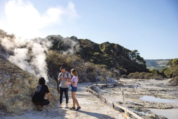 Toeristen staan bij een heetwaterbron in Hells Gate thermal reserve Rotorua
