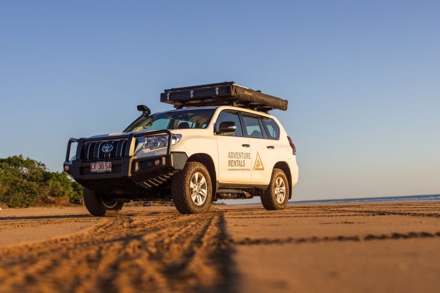 Adventure Rentals Toyota Prado 4WD camper op een strand geparkeerd